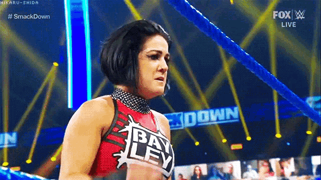 a woman is standing in a wrestling ring with a blue rope .