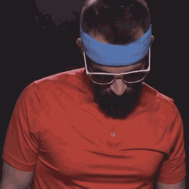a man wearing sunglasses and a blue headband looks down