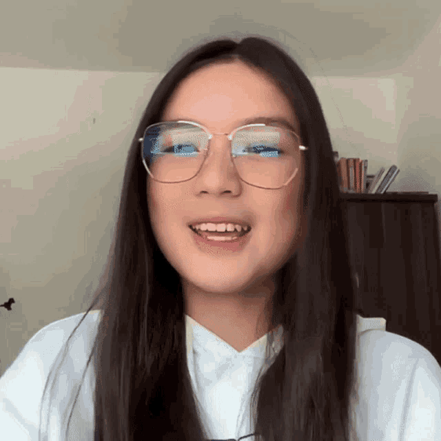 a young woman wearing glasses and a white shirt smiles