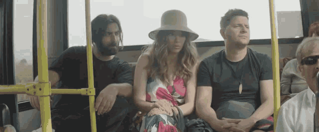 a group of people are sitting on a bus including a woman in a hat