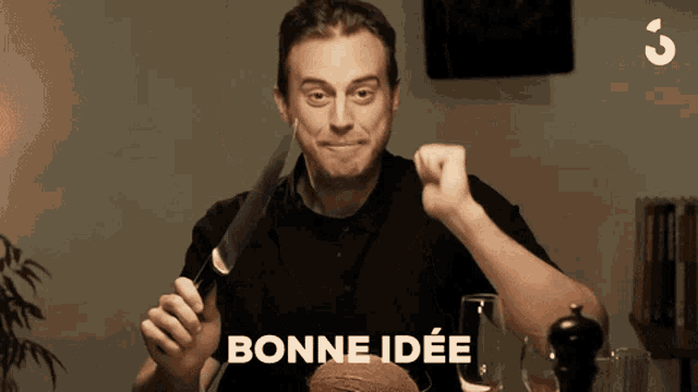 a man is holding a knife in front of his face and says bonne idee