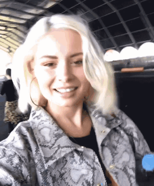 a woman wearing a snake print jacket smiles for a picture