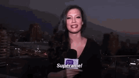 a woman is holding a microphone and saying superame .