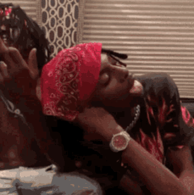 a man wearing a bandana and a watch is laying on another man 's lap