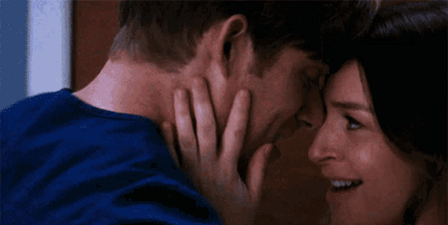 a man and woman are touching each other 's faces and smiling