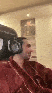 a man wearing headphones and a red robe is sitting in a chair