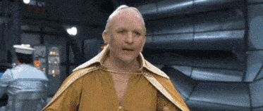 a man in a gold cape is standing in a room with a sign that says ' emergency exit ' on it