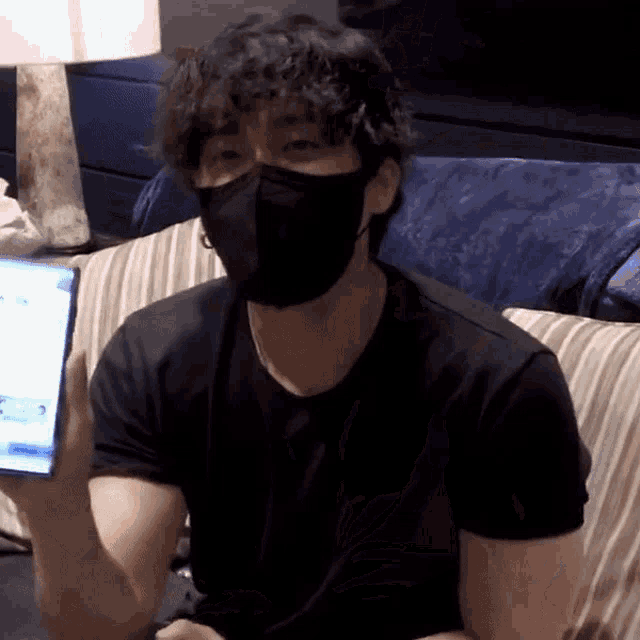 a man wearing a mask sits on a couch