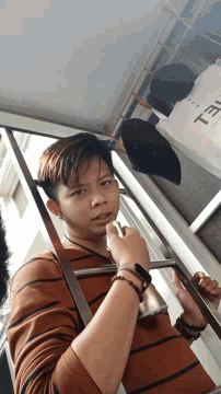 a young man looks down at something while holding a cell phone next to a bag that says tel