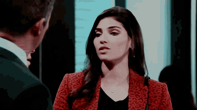 a woman in a leopard print jacket talks to a man in a suit