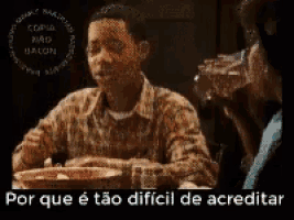 a man is sitting at a table with a bowl of food and the words por que e tão dificil de acreditar