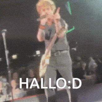 a man is playing a guitar and singing into a microphone on a stage with the words hallo : d above him .