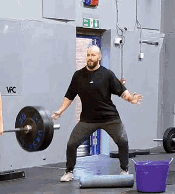 a man is squatting down with a barbell in his hands in a gym .