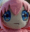 a close up of a pink stuffed animal with blue eyes and a sad face .