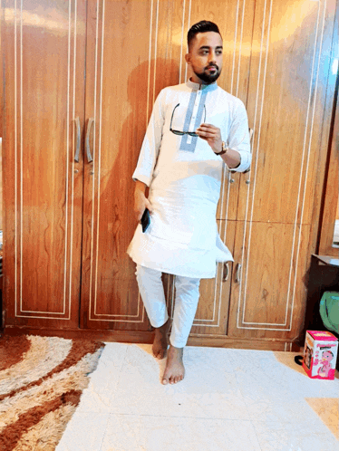 a man in a white shirt and pants stands in front of a closet
