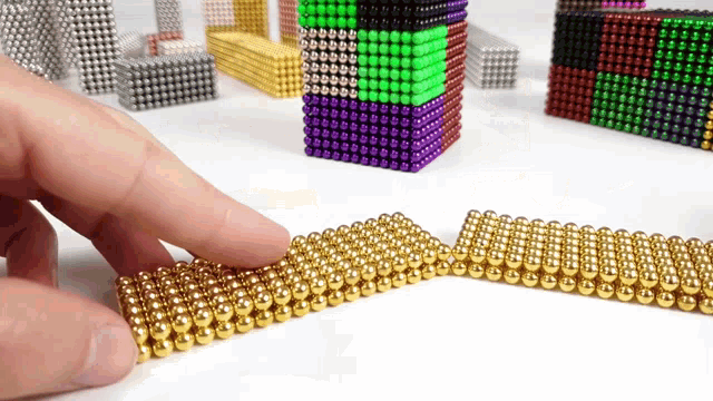 a person is playing with a bunch of different colored magnetic beads