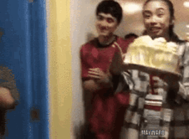 a girl is holding a cake in front of a group of people