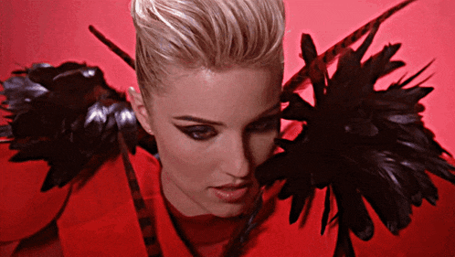 a woman in a red dress with black feathers on the shoulders