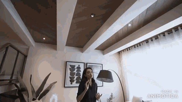 a woman is standing in a living room with a lamp and the words made in animatica on the bottom