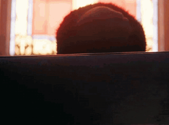 a person 's head is visible through a window with a red curtain