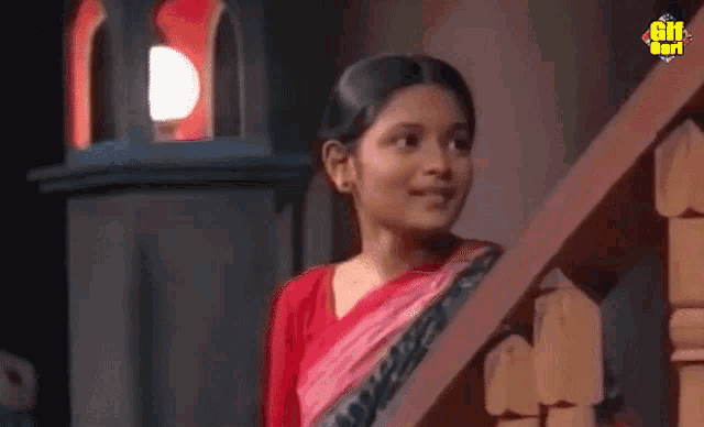 a girl in a red shirt is standing on a set of stairs with a gif written on the bottom right