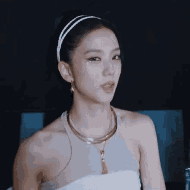 a woman wearing a necklace and a headband looks at the camera