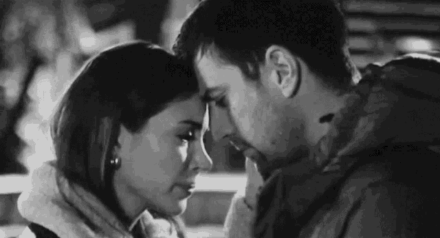 a black and white photo of a man and a woman looking into each other 's eyes .