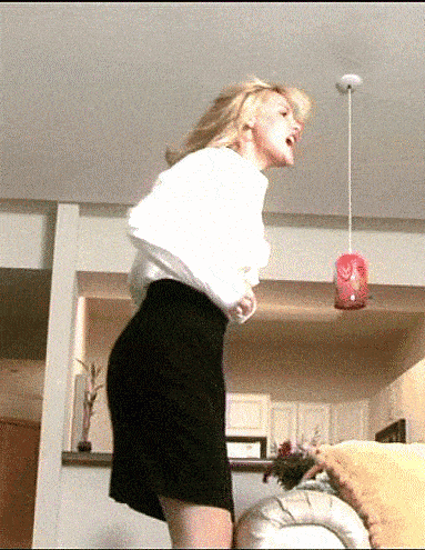 a woman in a white shirt and black skirt is standing in front of a couch .