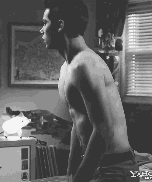a shirtless man is standing in front of a window with yahoo movie written on the bottom of the image