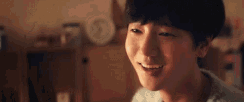 a young man is smiling and looking at the camera while sitting in front of a computer .