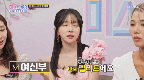 a woman in a pink dress with flowers on her shoulder is talking to another woman