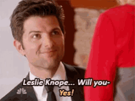 a man in a suit and tie is asking a woman if she will marry him