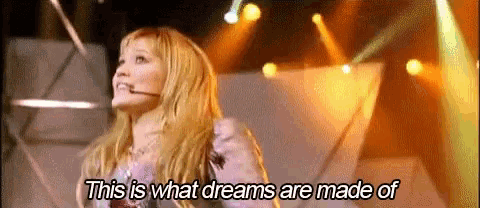 a woman is standing on a stage with a microphone in her mouth .