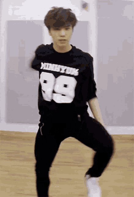 a young man wearing a black shirt with the number 99 on it is dancing .