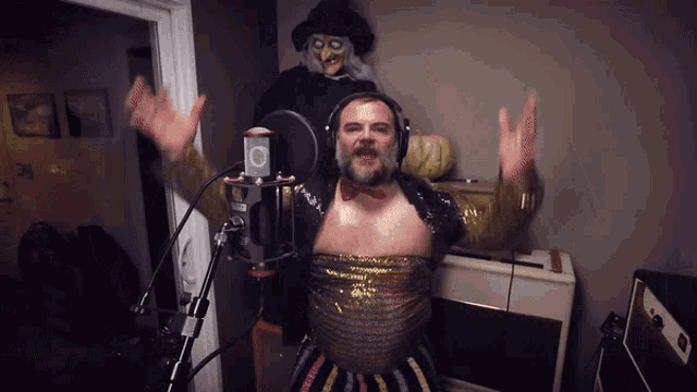 a man singing into a microphone in front of a witch
