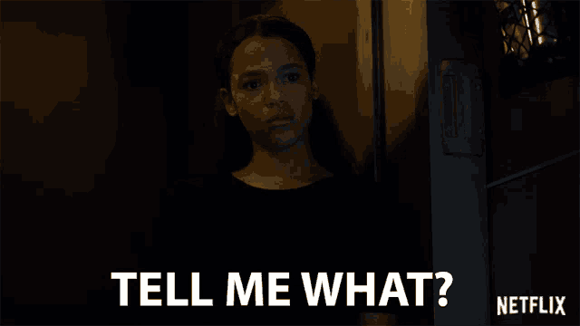 a girl is standing in a dark room and says tell me what