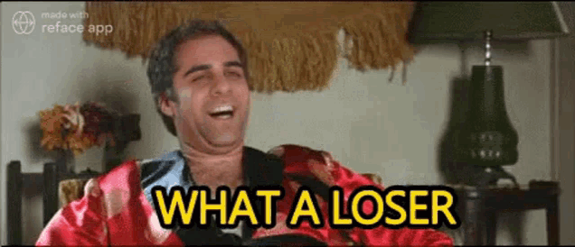 a man in a red robe is sitting in a chair and laughing with the words `` what a loser '' .