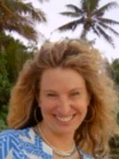 a woman in a blue and white shirt is smiling in front of a palm tree