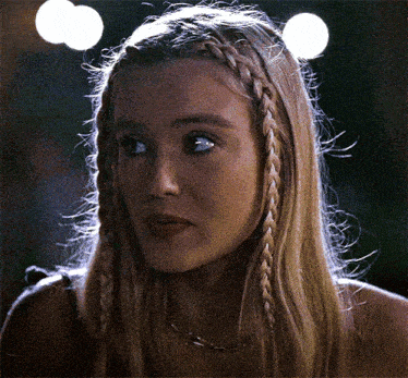 a close up of a woman 's face with braided hair