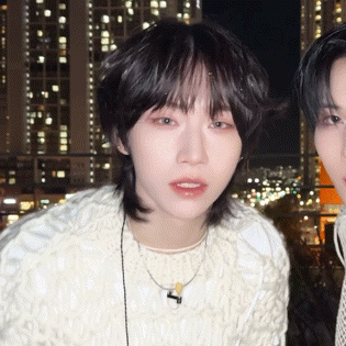 a close up of a person wearing a white sweater and a necklace