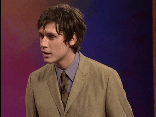 a man in a suit and tie stands in front of a purple backdrop
