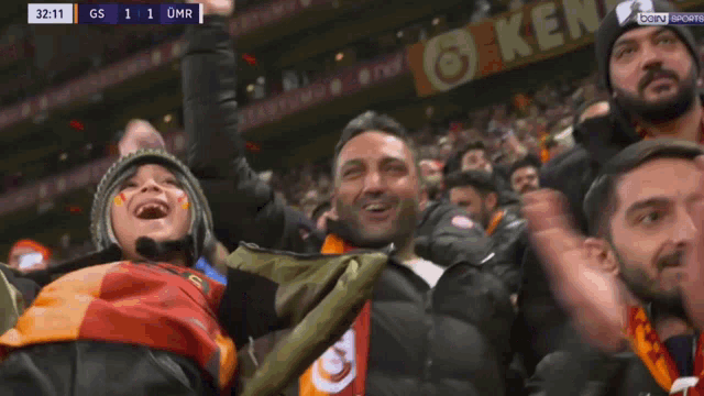 a crowd of people watching a sports game with a score of gs 1 1 omr