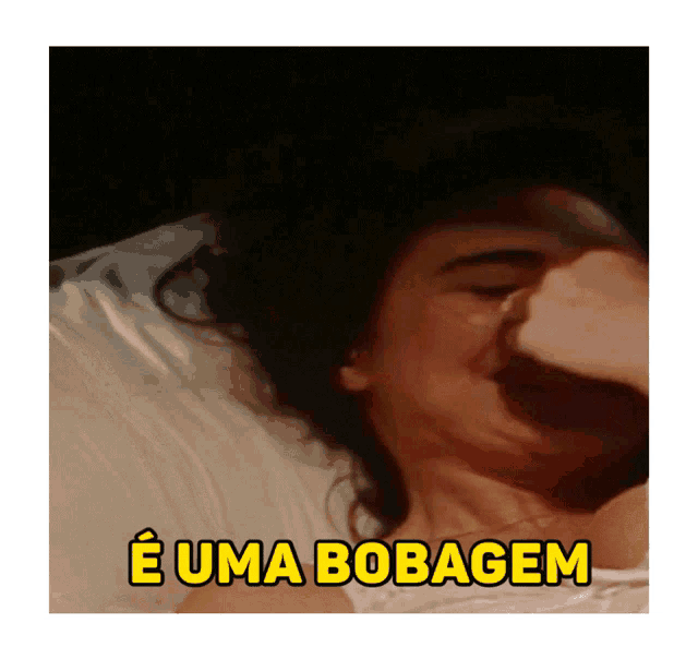 a woman laying in bed with the words e uma bobagem above her head