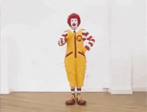 a mcdonald 's clown is standing in a room with his hands on his hips