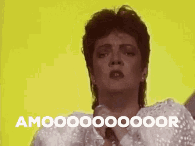 a woman is singing into a microphone with the words amooooooooor written on the screen behind her