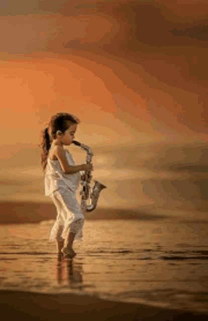 a little girl playing a saxophone on the beach