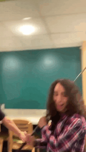 a woman in a plaid shirt is playing a violin in a room .