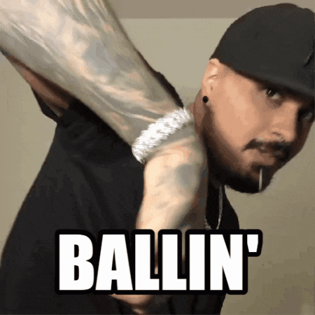 a man wearing a hat and a bracelet holds a large object over his shoulder and says ballin '