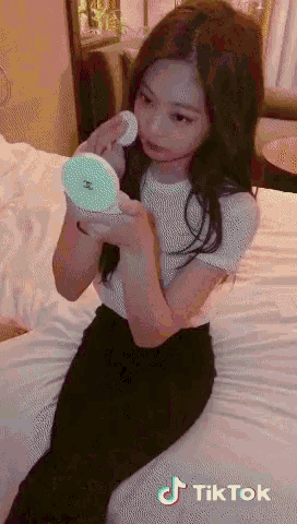 a girl is sitting on a bed looking at herself in a mirror with tiktok written on the bottom right