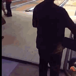 a man is standing in front of a bowling alley .
